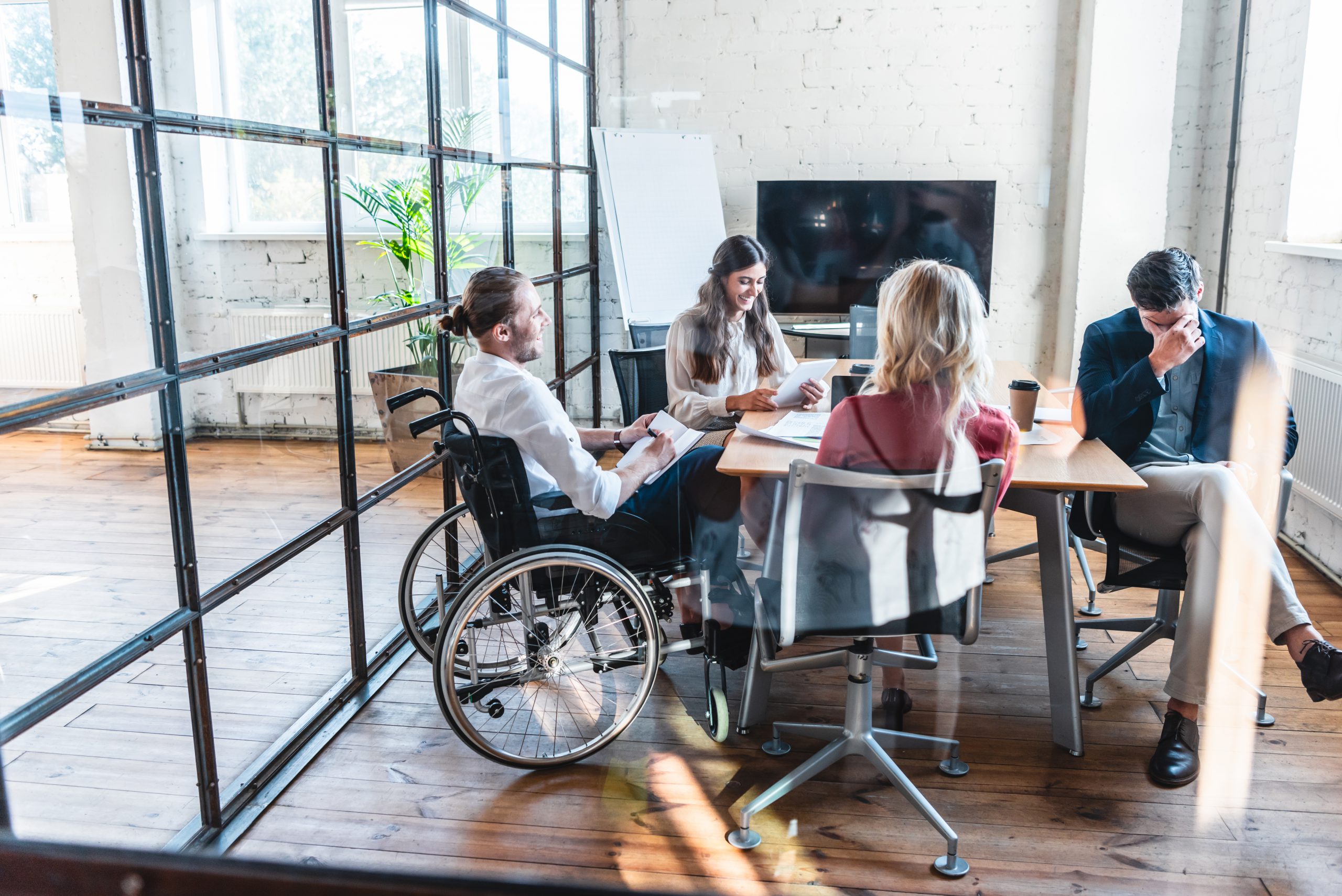 young businessman in wheelchair working with colleagues in office